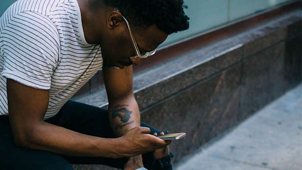 A man sat down outside using his phone.
