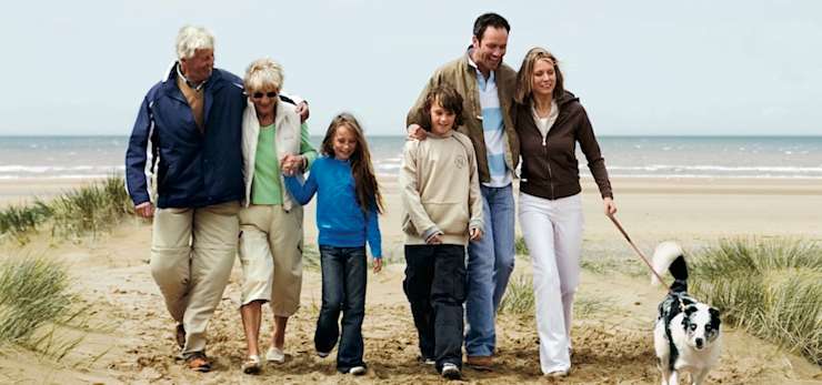 Family walking on a beach with a dog.