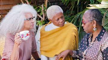 3 ladies chatting in a garden with a cup of tea.