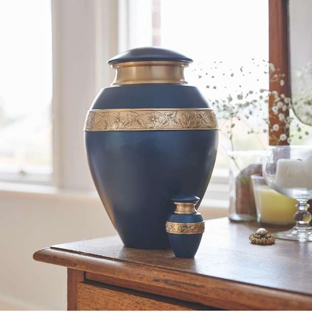 Blue urn with gold ornamentation in two sizes on a wooden sideboard