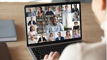 Woman on an online video call with multiple people on her laptop screen
