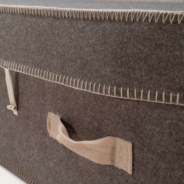 Close up of the grey wool coffin showing cream stitching and woven fabric handles