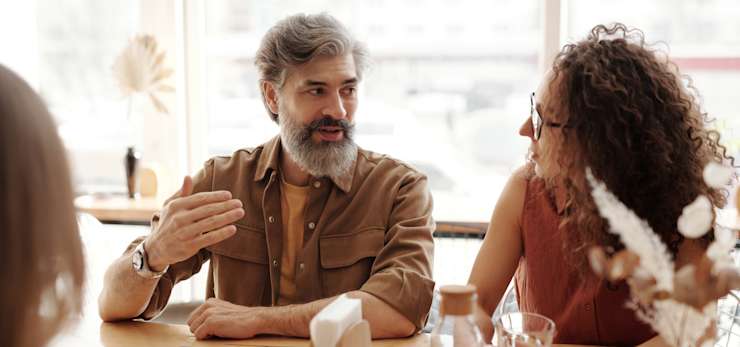 2 people having a conversation at a table with a group