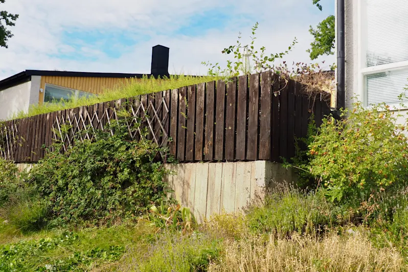 Ursprungligt exempel på staket av brädor och formgjuten stödmur.