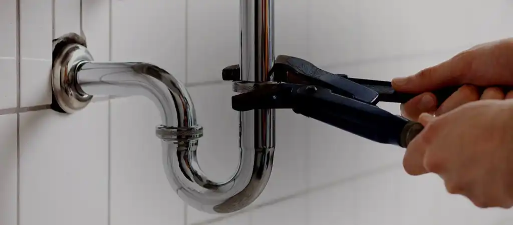 person using a wrench to unscrew a pipe