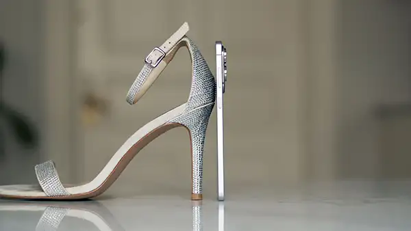 En Samsung Galaxy S25 Edge stilt opp sammen med en høyhælet sko, viser at telefonen er veldig slank