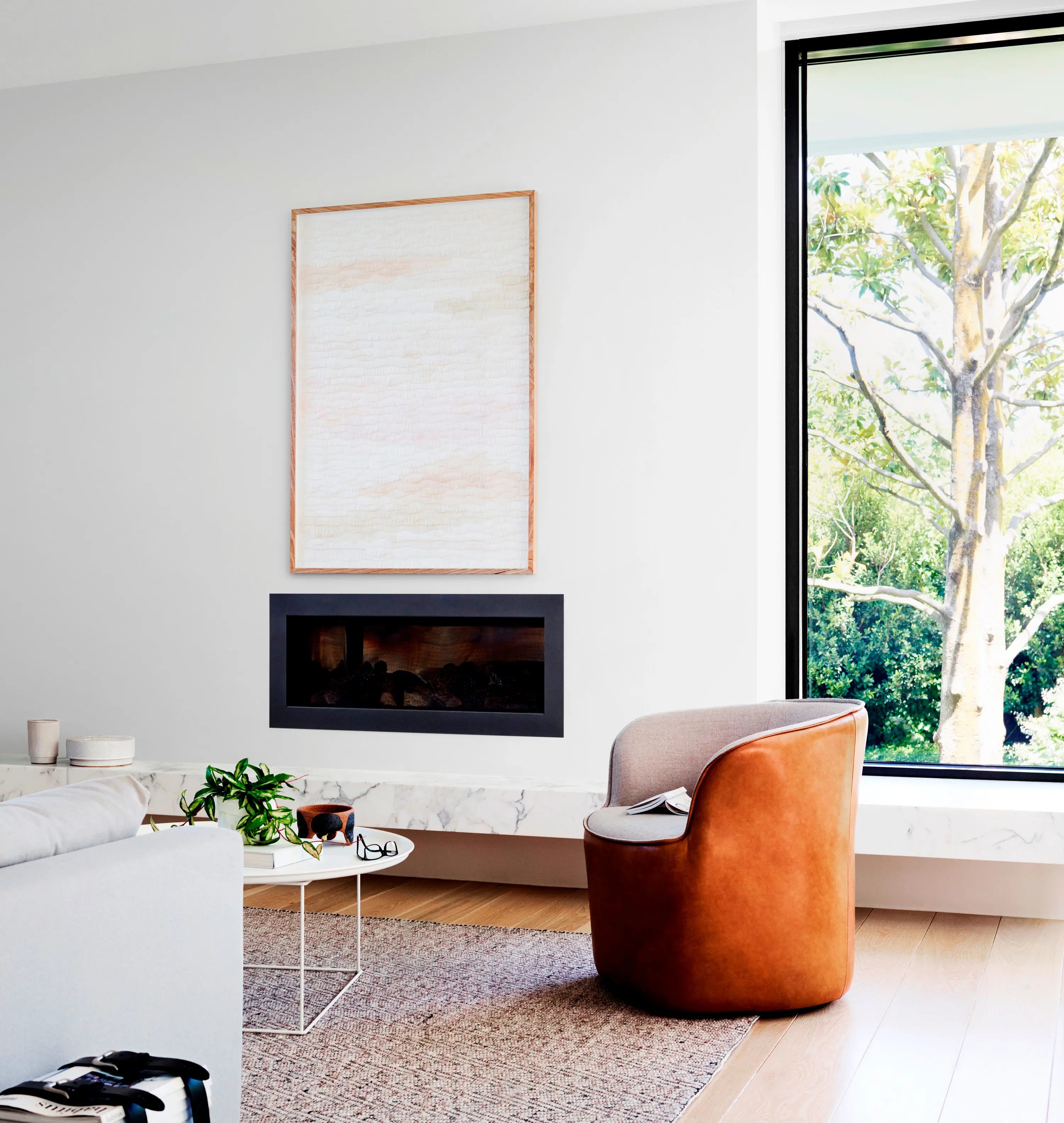 White living room with modern fireplace and tub-style brown leather armchair