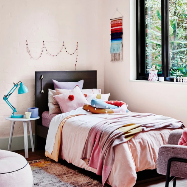Pink bedroom with decorated girl's bed with furniture surrounding.