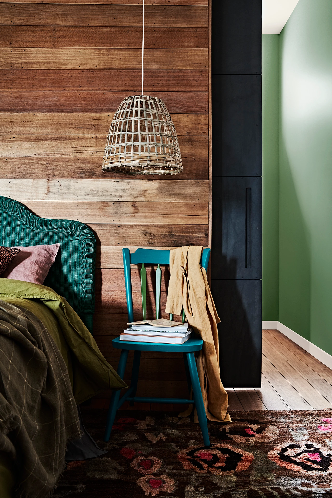 Bedroom with wooden feature wall and green headboard.
