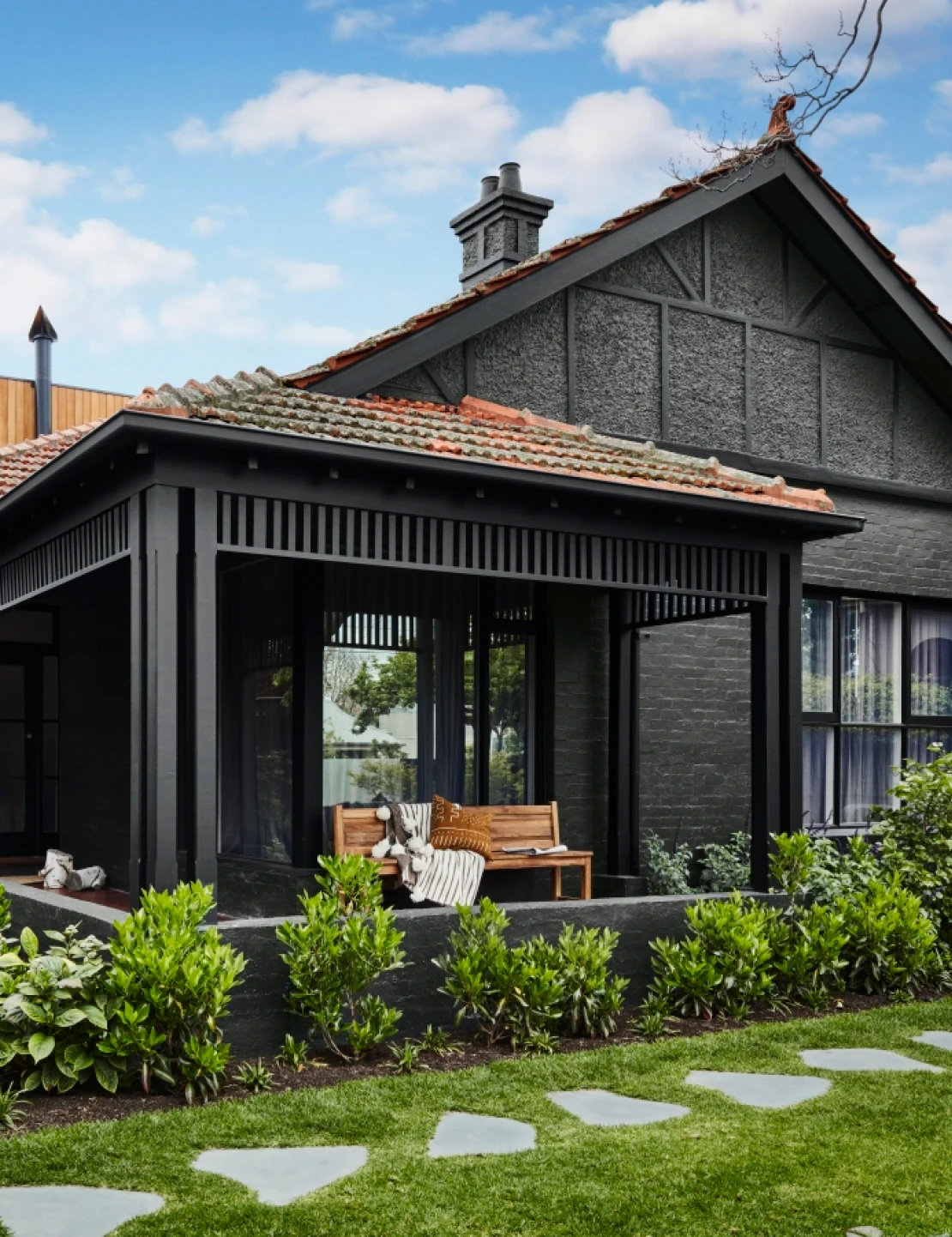 Dark exterior style house with Dulux Rāwene and Castlecliff colours and a green garden.