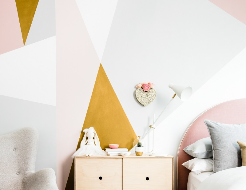 child's bedroom with feature wall in geometric patterns including paint in gold, pinks and greys.