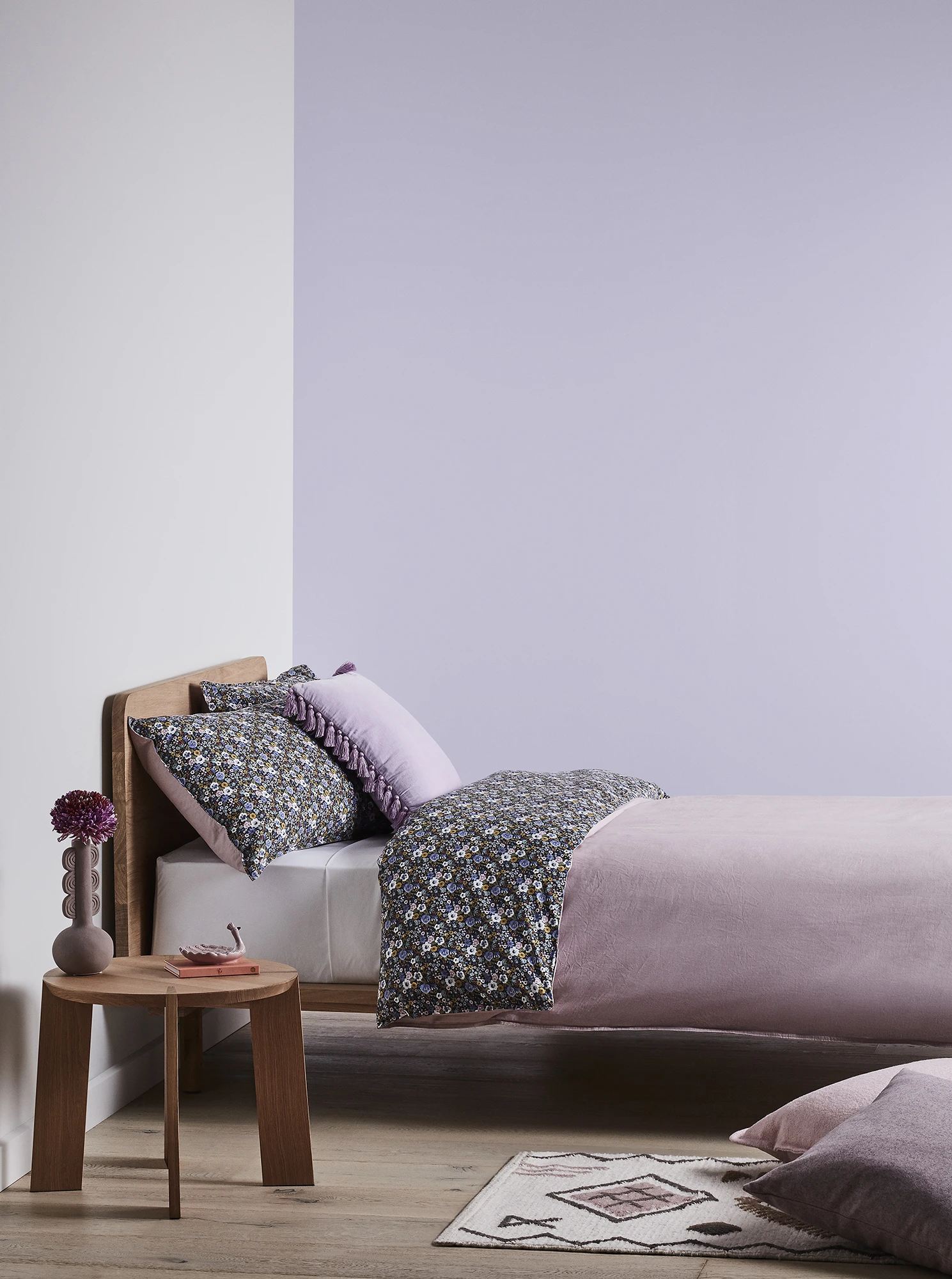 Pink and purple themed bedroom showing bed and side table.
