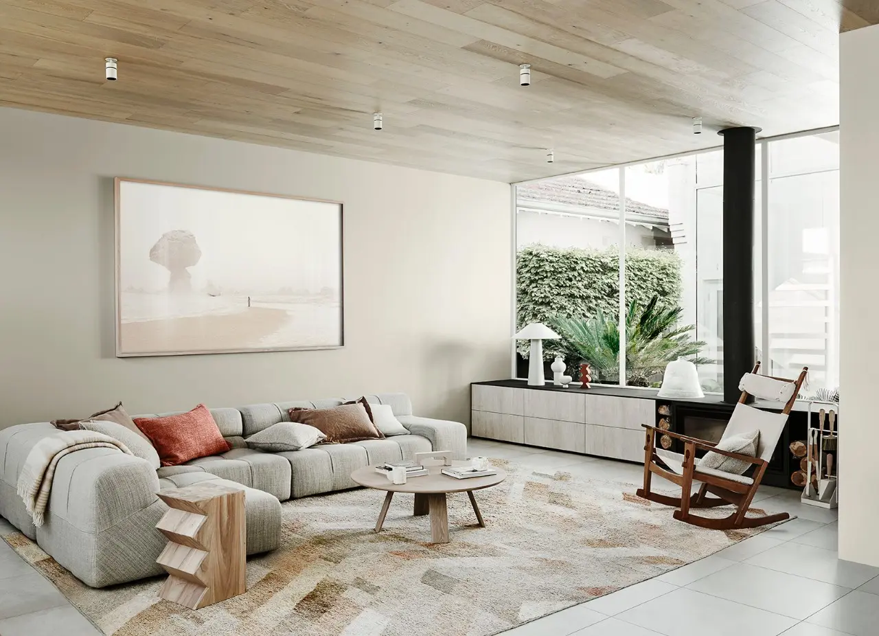 Neutral living room with sectional couch, rocking chair, timber coffee table and wall-length console.