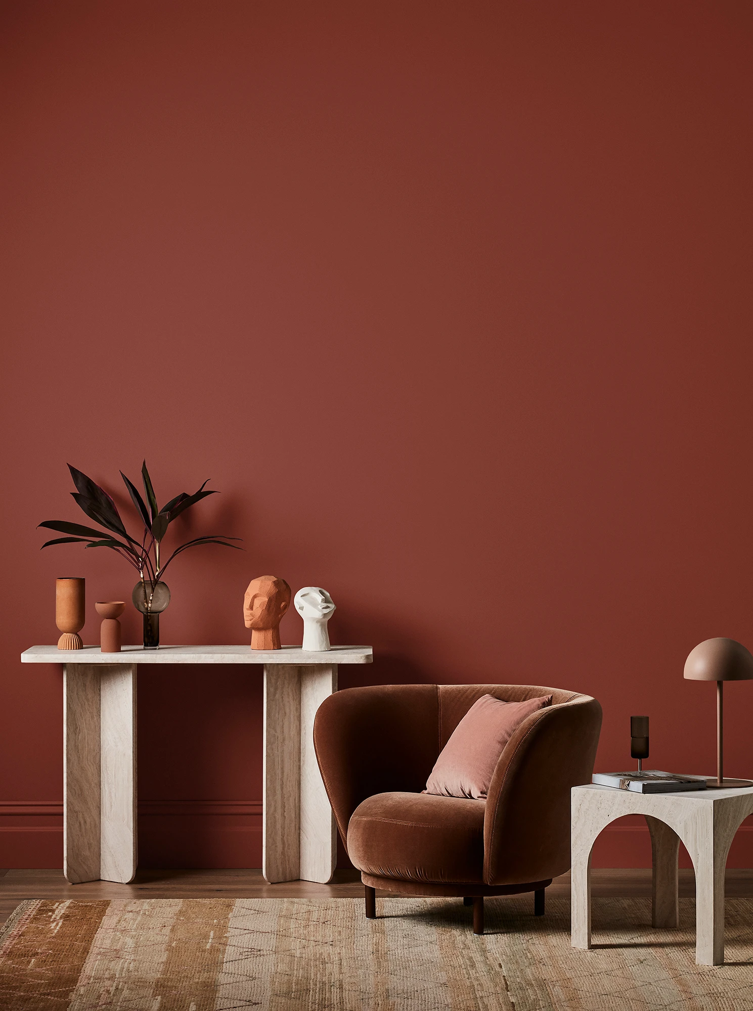Brown living room with white console table with terracotta and white decor, velvet brown armchair and neutral side table with brown lamp.
