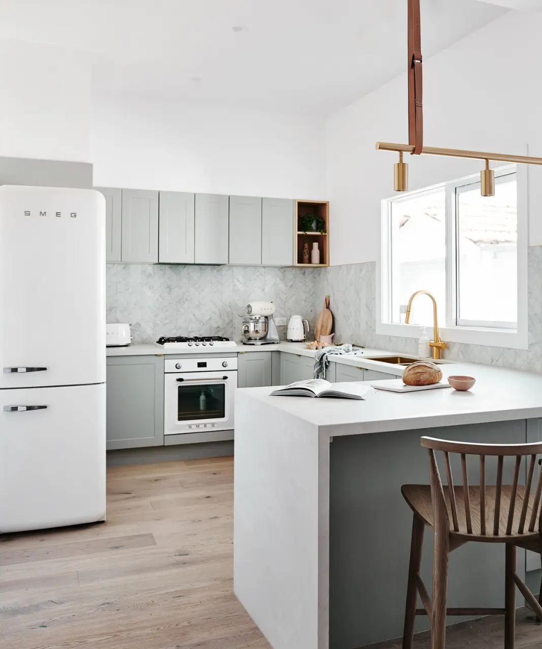 Neutral coloured kitchen with white Smeg fridge and wooden floor
