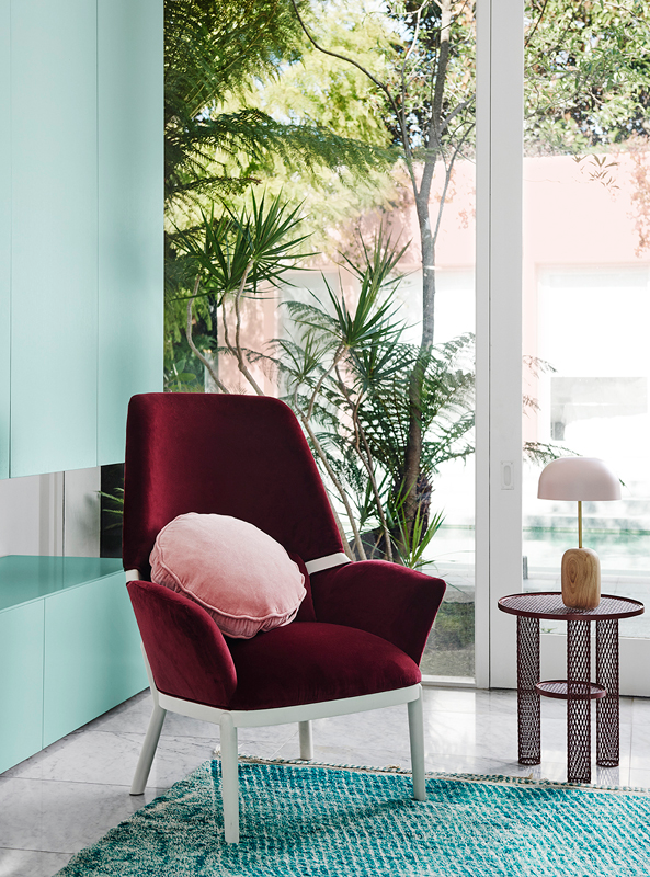 A red velvet armchair in a teal-painted room