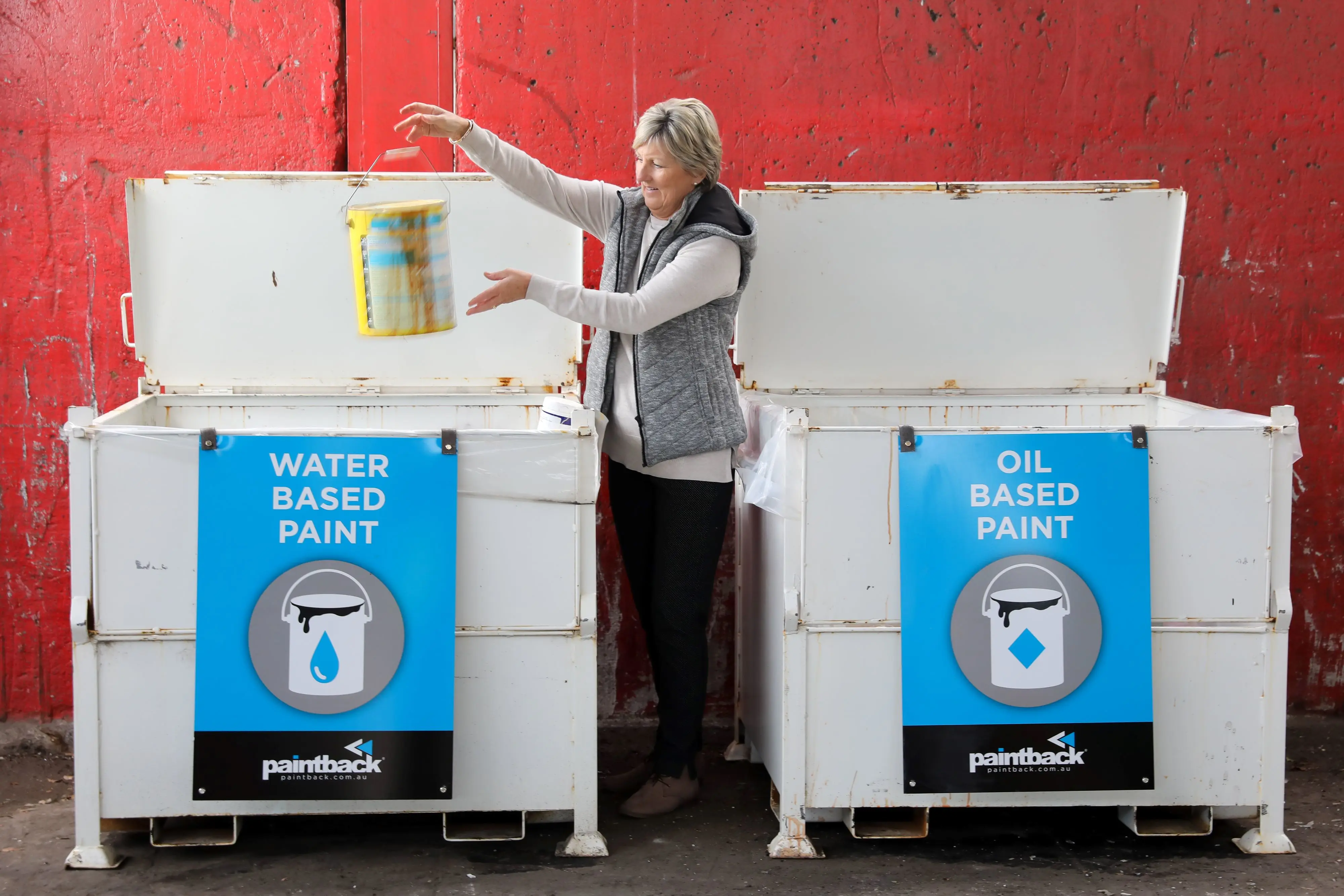 Woman placing used paint tin in recycling