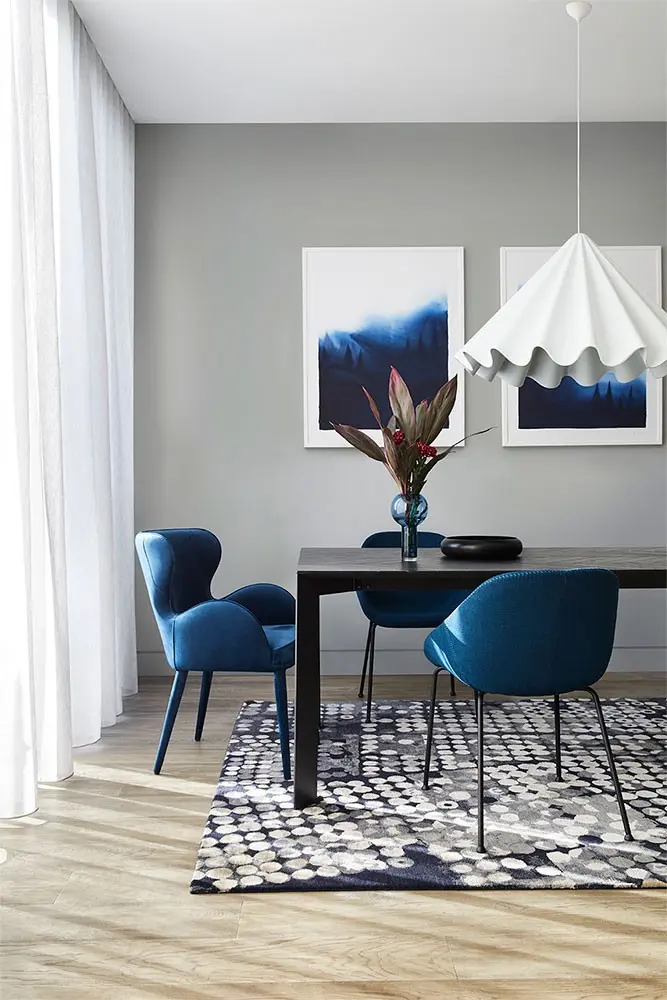 interior grey dining room with closeup on blue chairs and lamp.