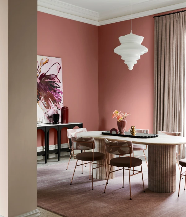 Dining room with pink walls and white pendant light