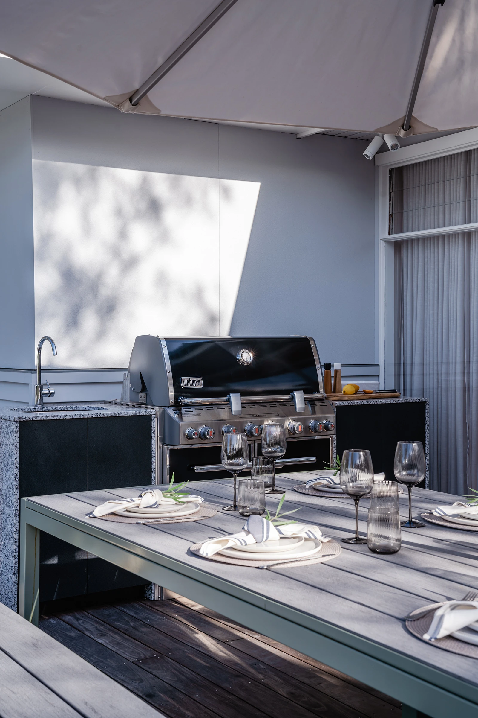 Outdoor dining table on patio with barbeque and outdoor kitchen