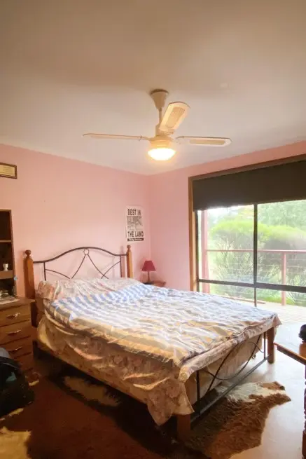 Pink bedroom and white ceiling with timber and metal bed 