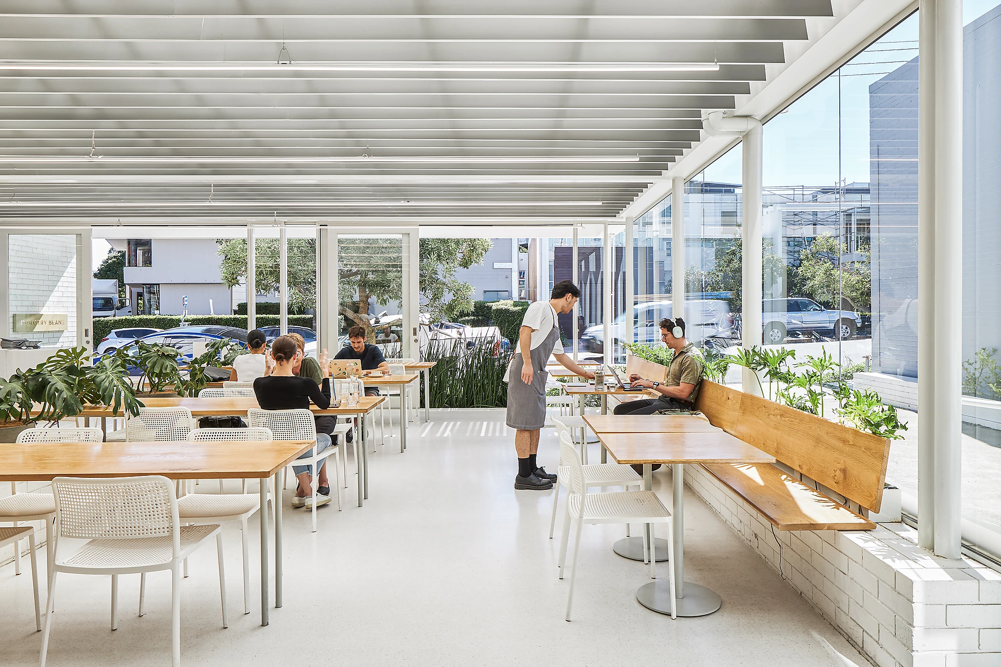White cafe, wooden seating and tables, floor to ceiling windows