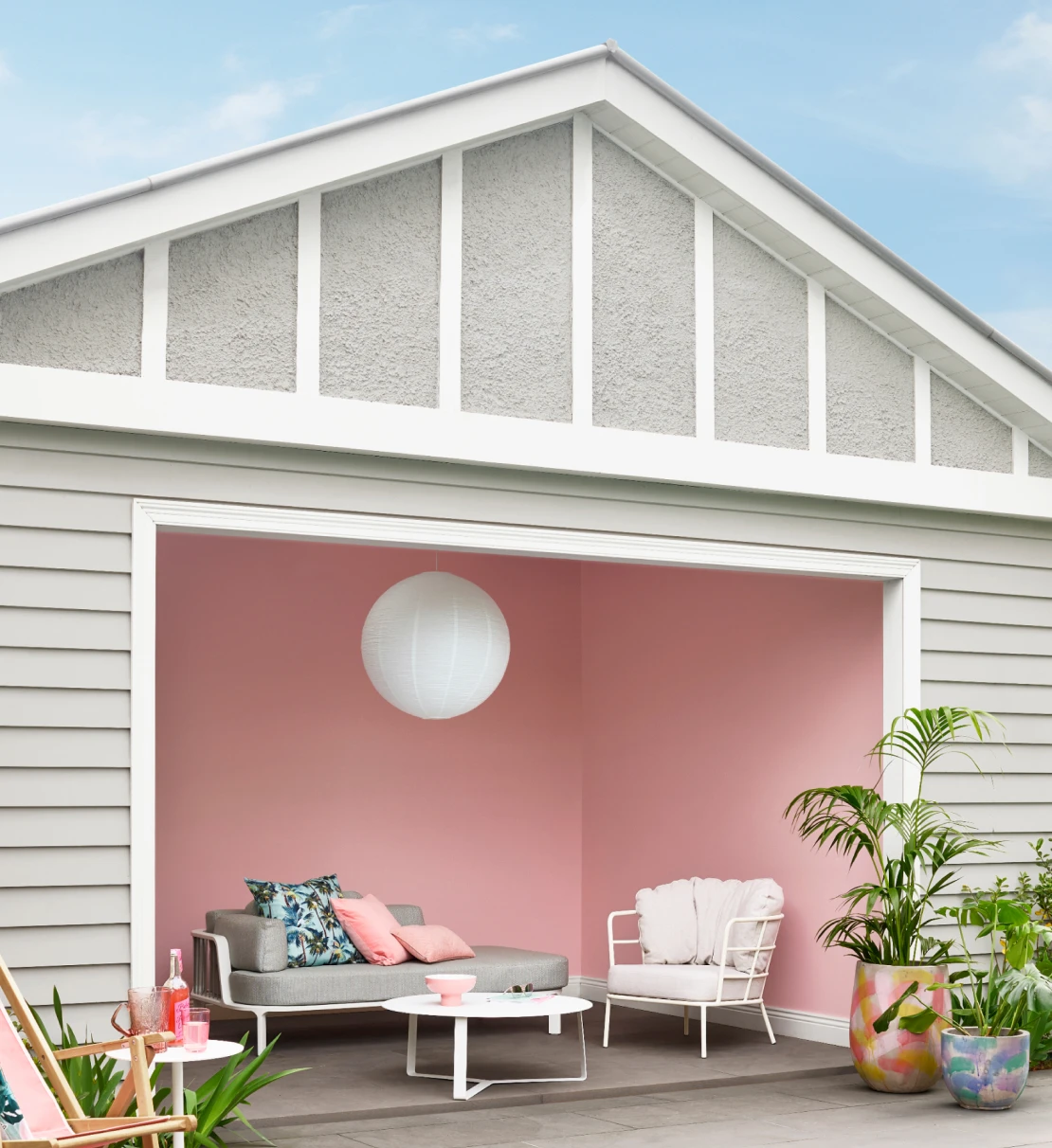 Pool house with Pink Dust coloured interior walls, Tranquil Retreat coloured weatherboards and Snowy Mountains Half trims. Area is decorated with lounge furniture and greenery. 