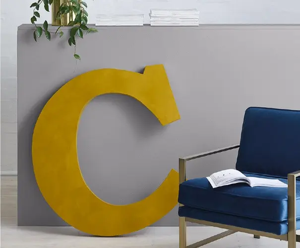 view of C with gold effect next to blue armchair 