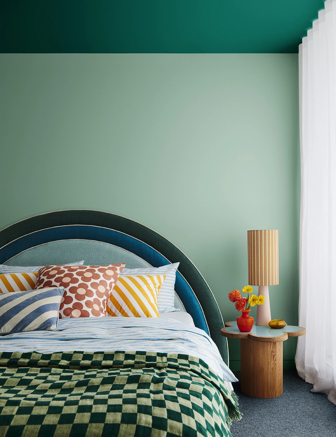 Green bedroom with check quilt and arched bedhead