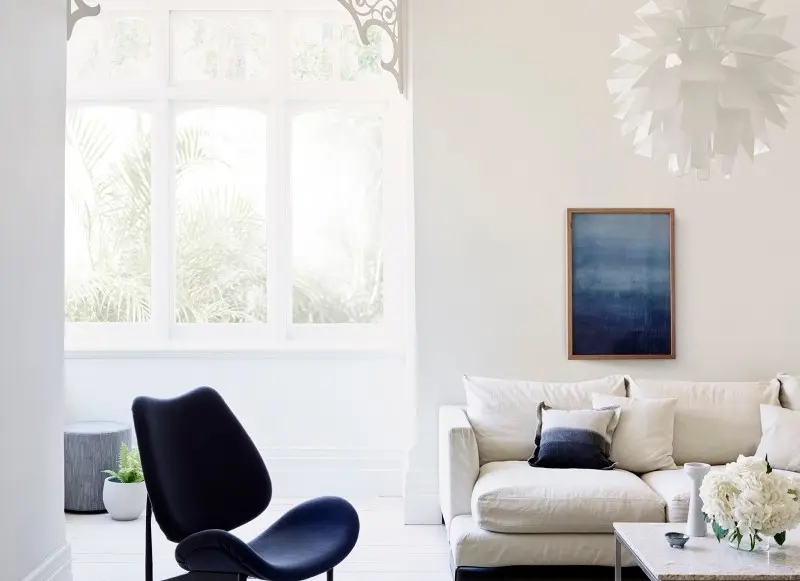 interior white lounge with blue chair and painting.