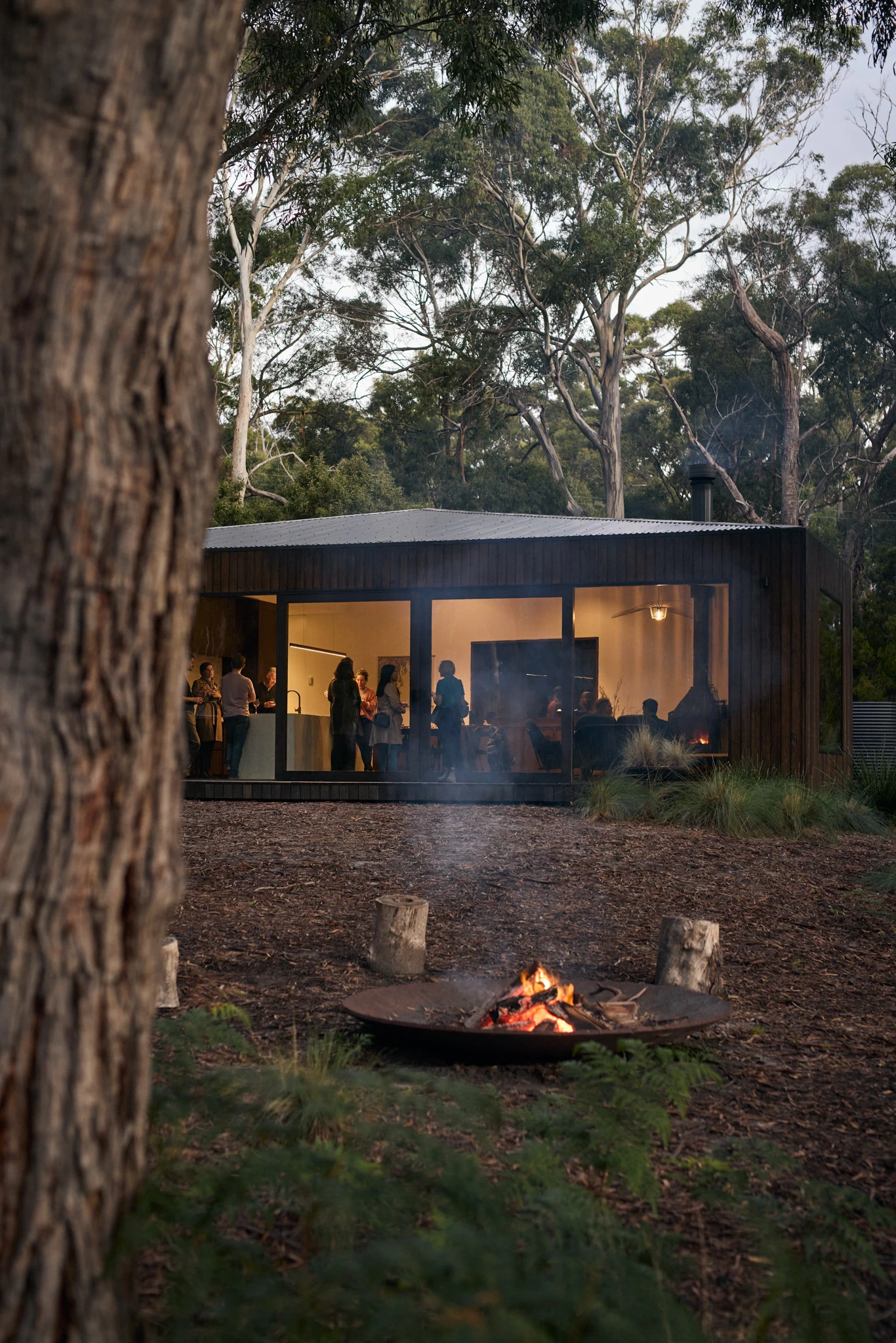 Lit fire pit near modern weatherboard house in Tasmanian bushland