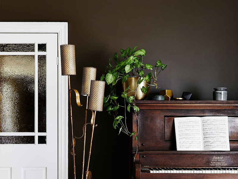 A brown wall with a piano against it. There is a book with music that is open on the piano.