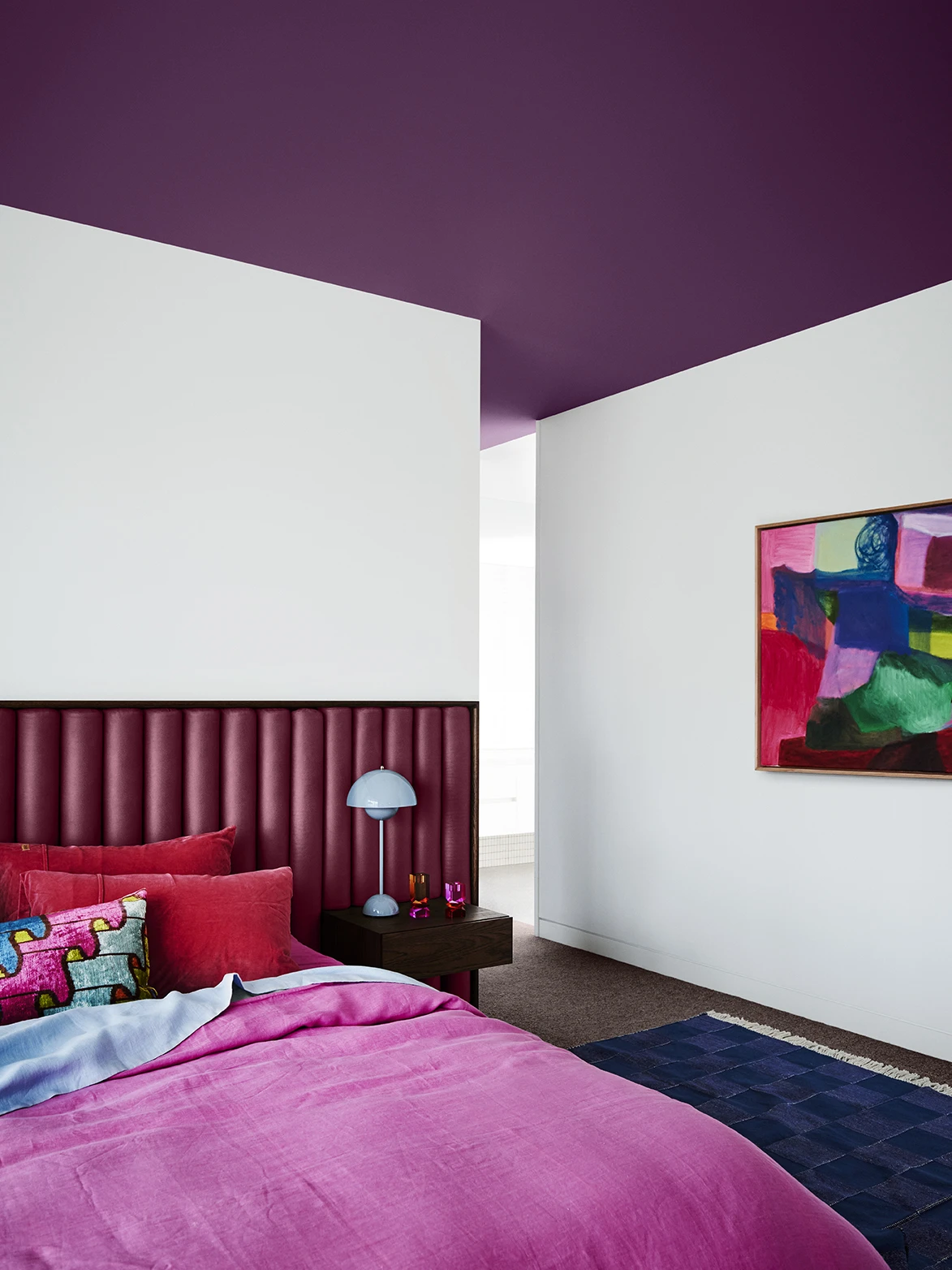 Bedroom with purple bedhead and ceiling and white walls