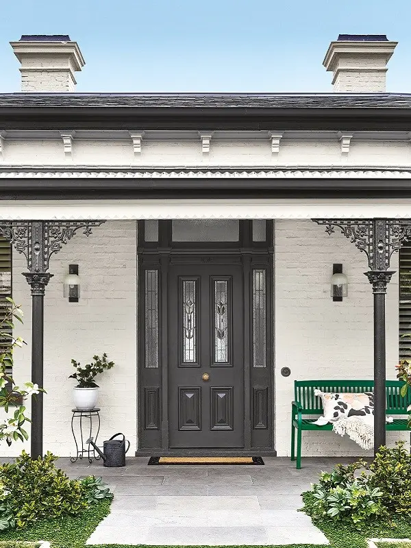 Grey and white traditional house with green bench on verandah