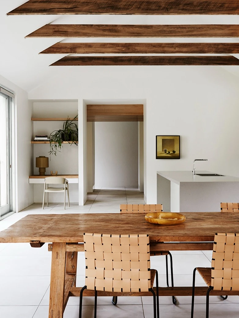White interior dining room with timber table and timber ceiling beams