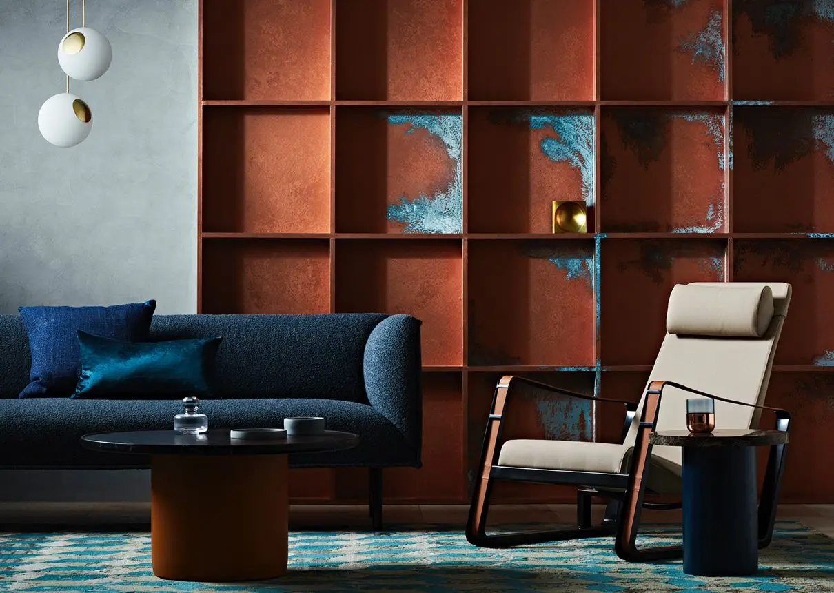 seating area, blue couch and cream chair in front of copper patina effect wall 