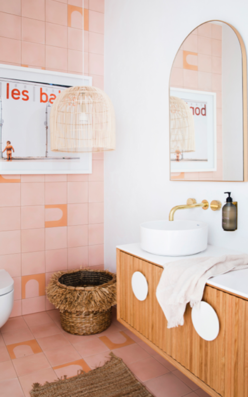 Hinterland white bathroom with white and timber vanity, arched mirror, peach tiles for feature wall and floor.