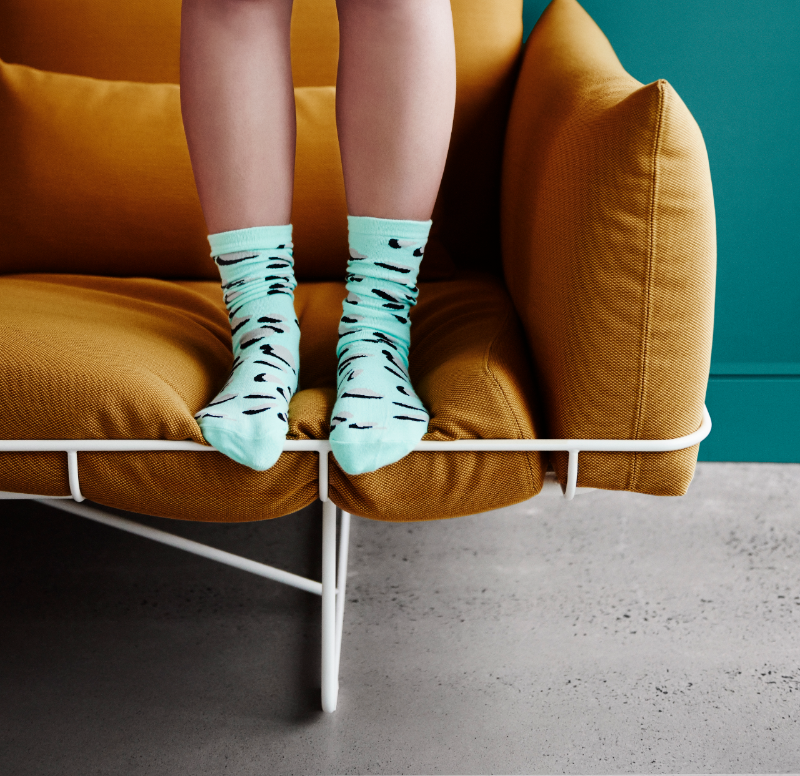 Person wearing socks standing on a yellow sofa with polished concrete floor in living room with walls in Dulux Deep Artic.