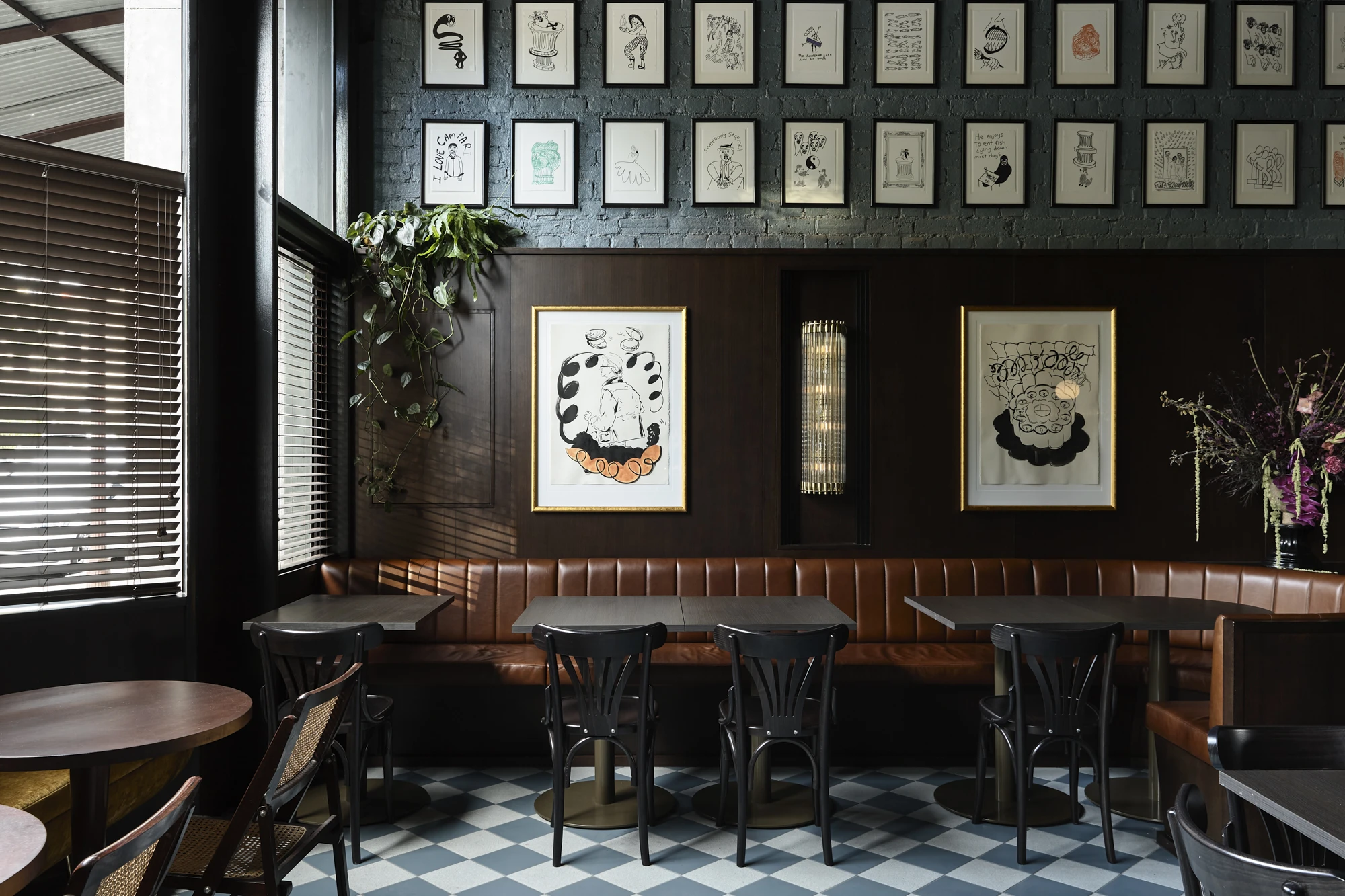 Dark-walled restaurant with artwork, leather banquette and black and white checkered floor