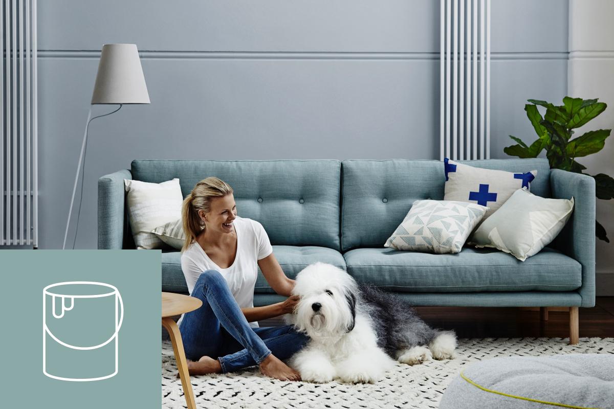 Woman on floor with Dulux dog against green couch with inset icon of paint can