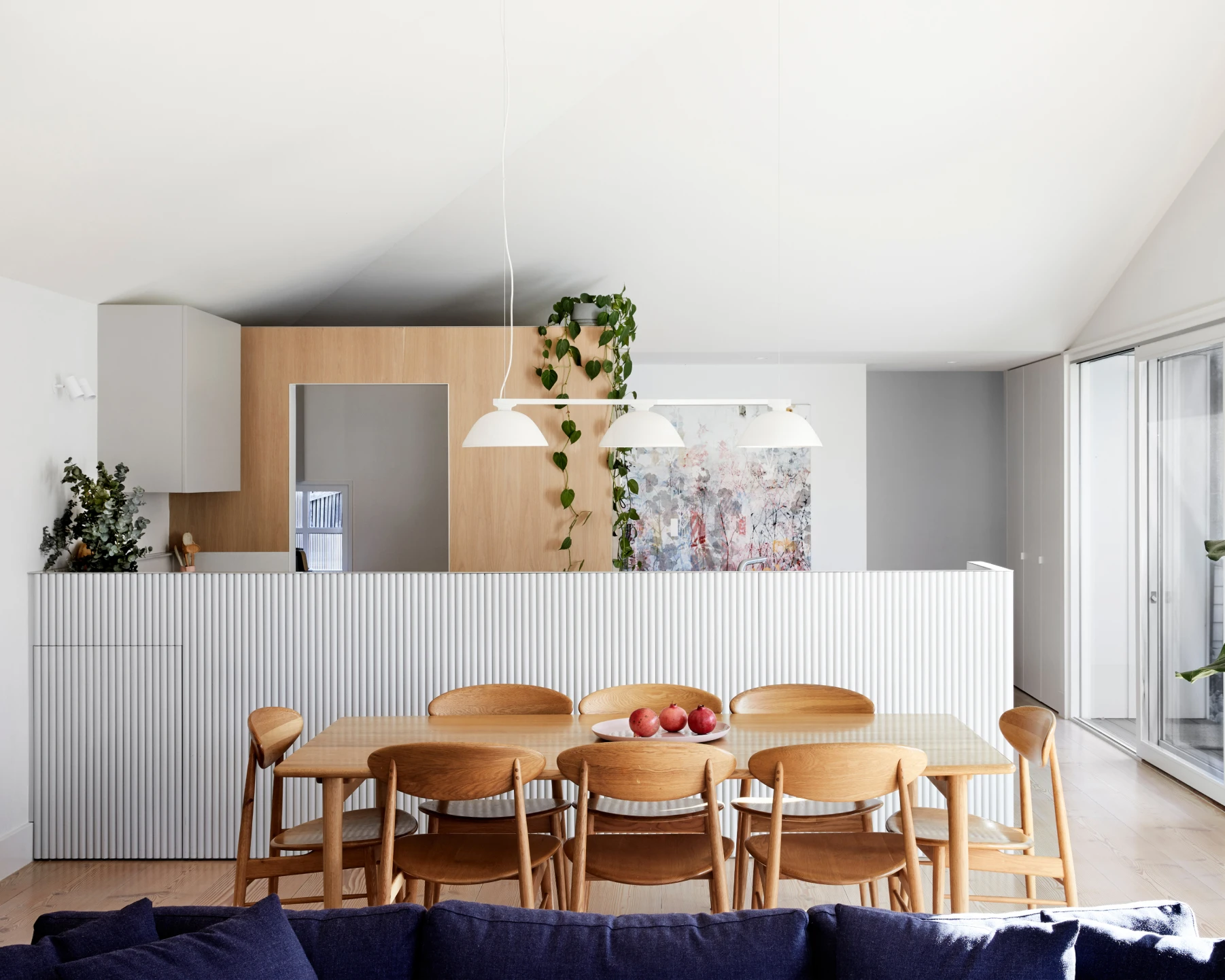 Kitchen and dining area with Natural White walls, bench backing and ceiling and including timber pantry and dining table.