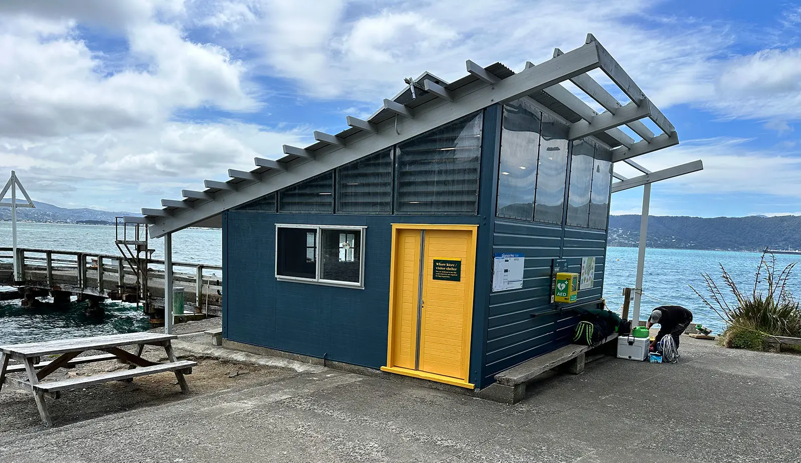 Whare Kiore with blue exterior and yellow door