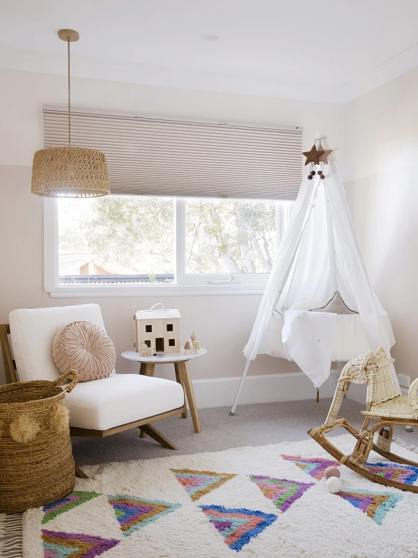 Airy neutral nursery with colourful rug and white tipi over cot