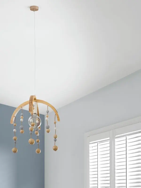 Blue and white walls with view of ceiling. Child's wooden toy mobile hanging from ceiling