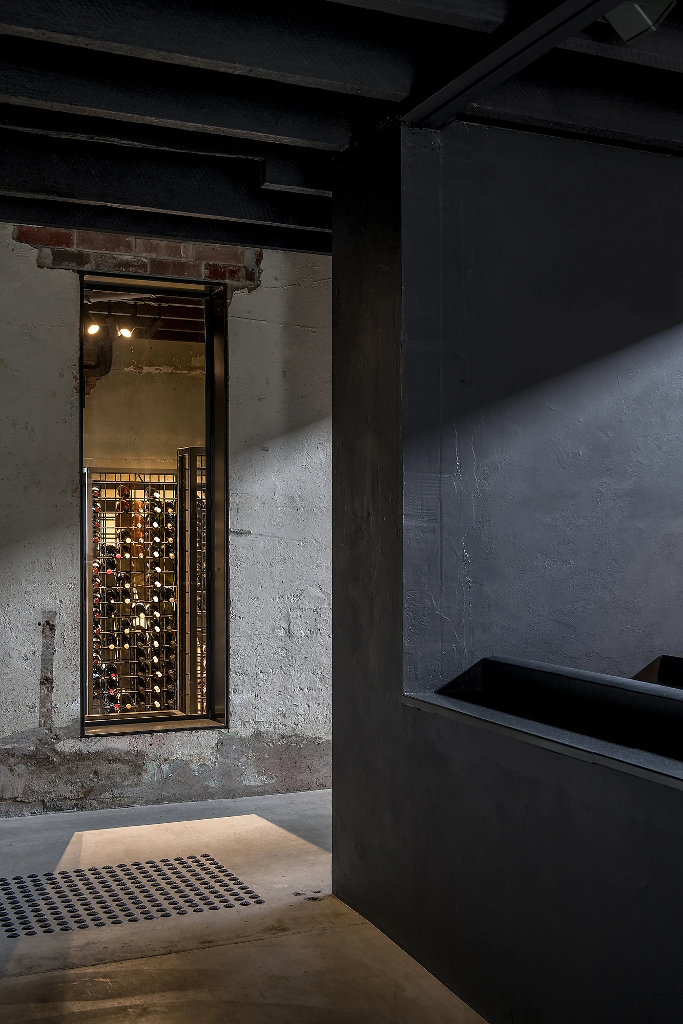 Concrete walls with view to glass window showcasing large wine rack.
