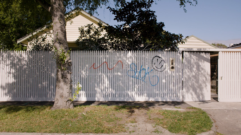 Cream picket fence with graffiti