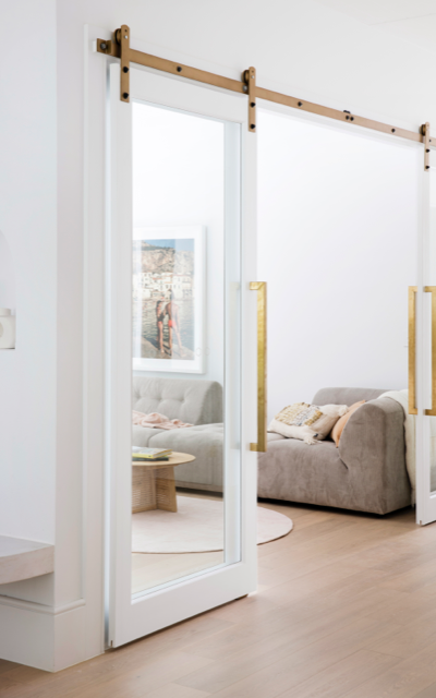 Hinterland Hideaway white living room with barn-style glass sliding doors with gold railing and handles