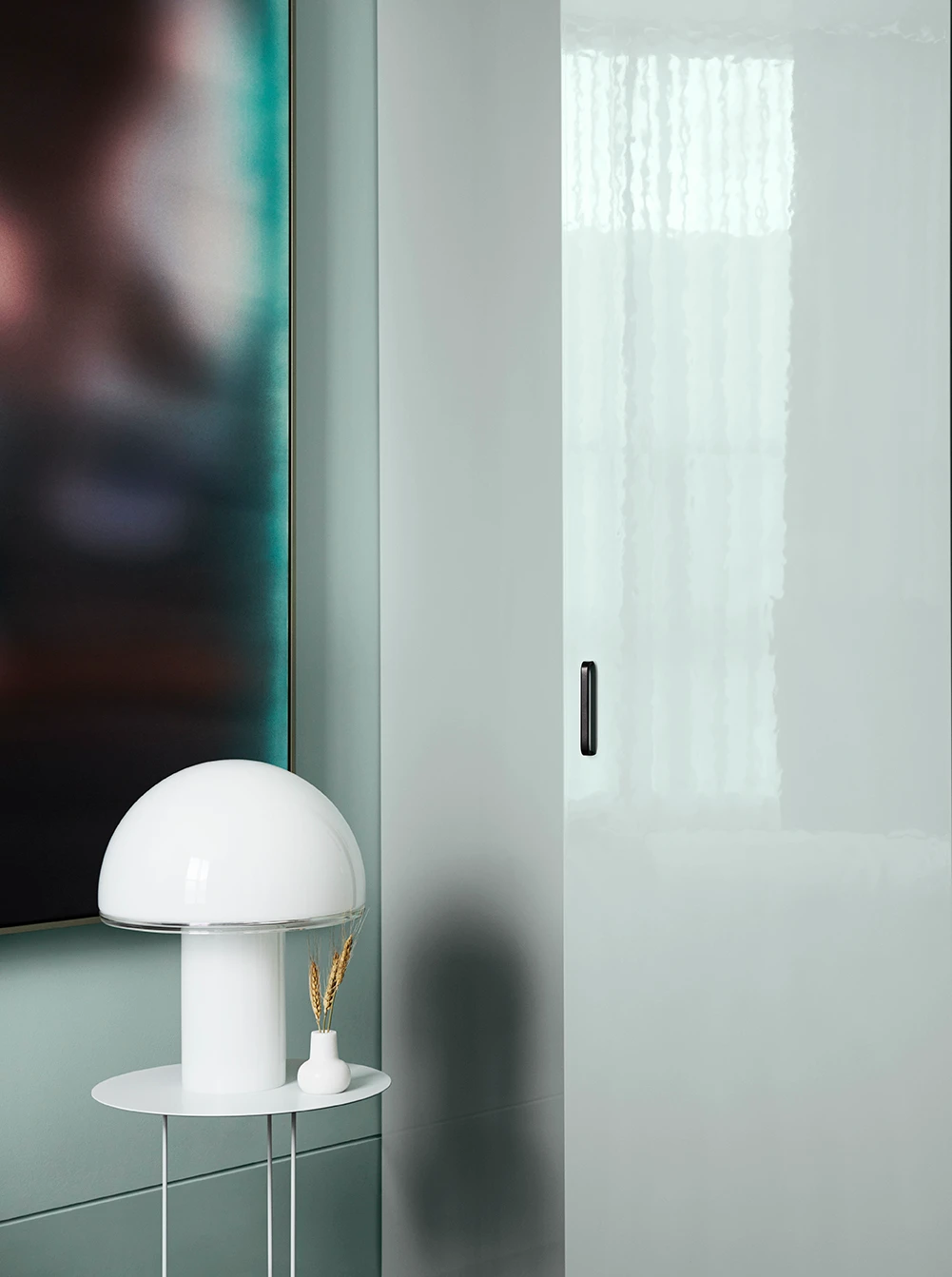 Light green walls with white side table and lamp.