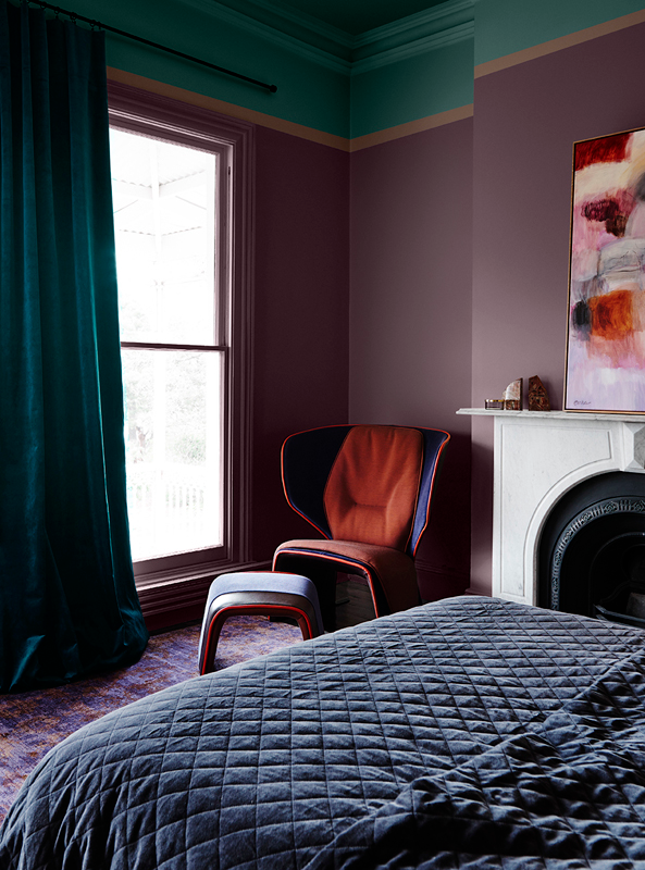 A navy and red armchair juxtaposed against the sheen of a purple bedroom wall