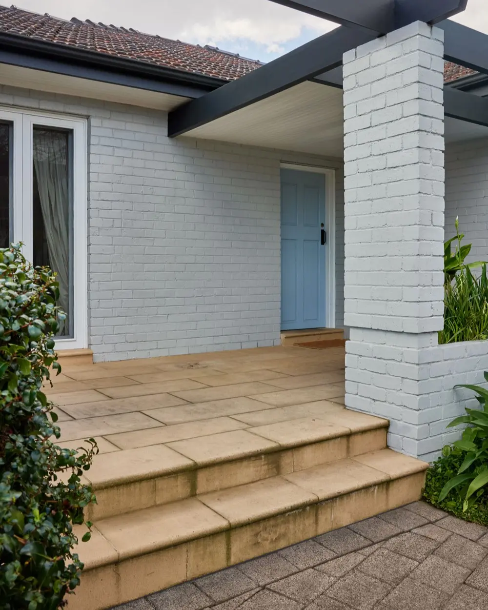 Sandstone pavers to patio entry of a white brick house.